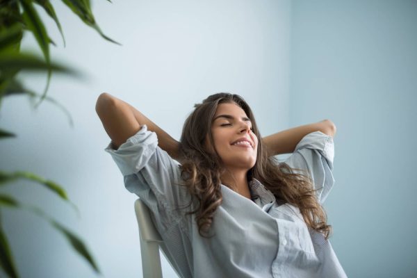 Femme assise, détendue et souriante pendant une séance de sophrologie